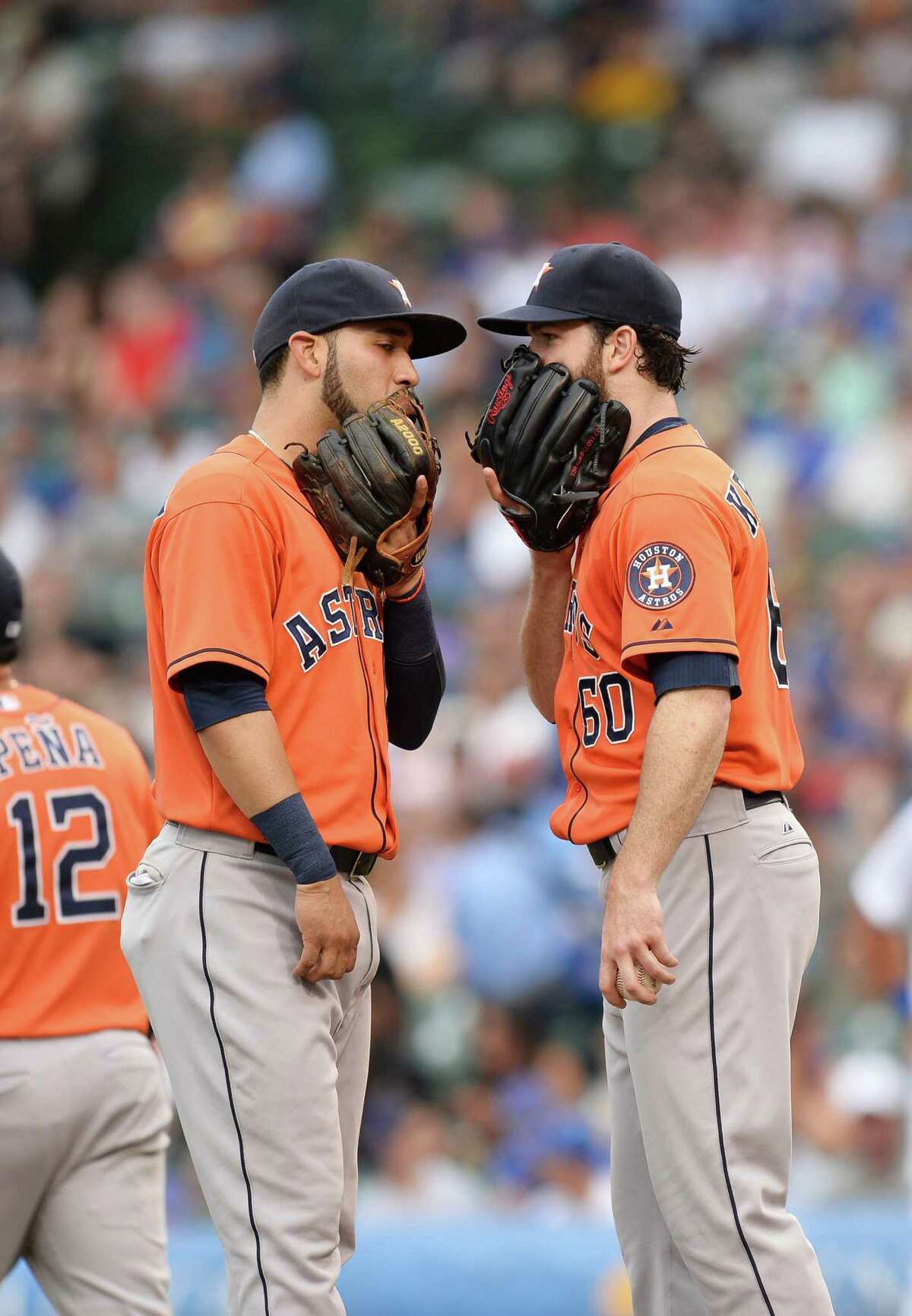 Proving you can't be too careful these days, Astros shortstop Marwin Gonzalez, left, and starter Dallas Keuchel try to keep their mound conversation private during the third inning.