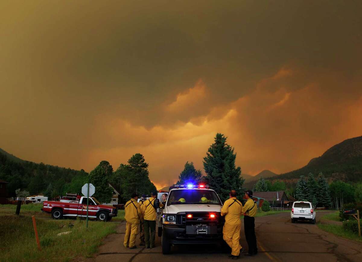 Firefighters stage in a residential area in South Fork, Colo., as they monitor a wildfire that burns west of town on Friday evening June 21, 2013. The town was evacuated and U.S. 160 that passes through it was closed. (AP Photo/Ed Andrieski)