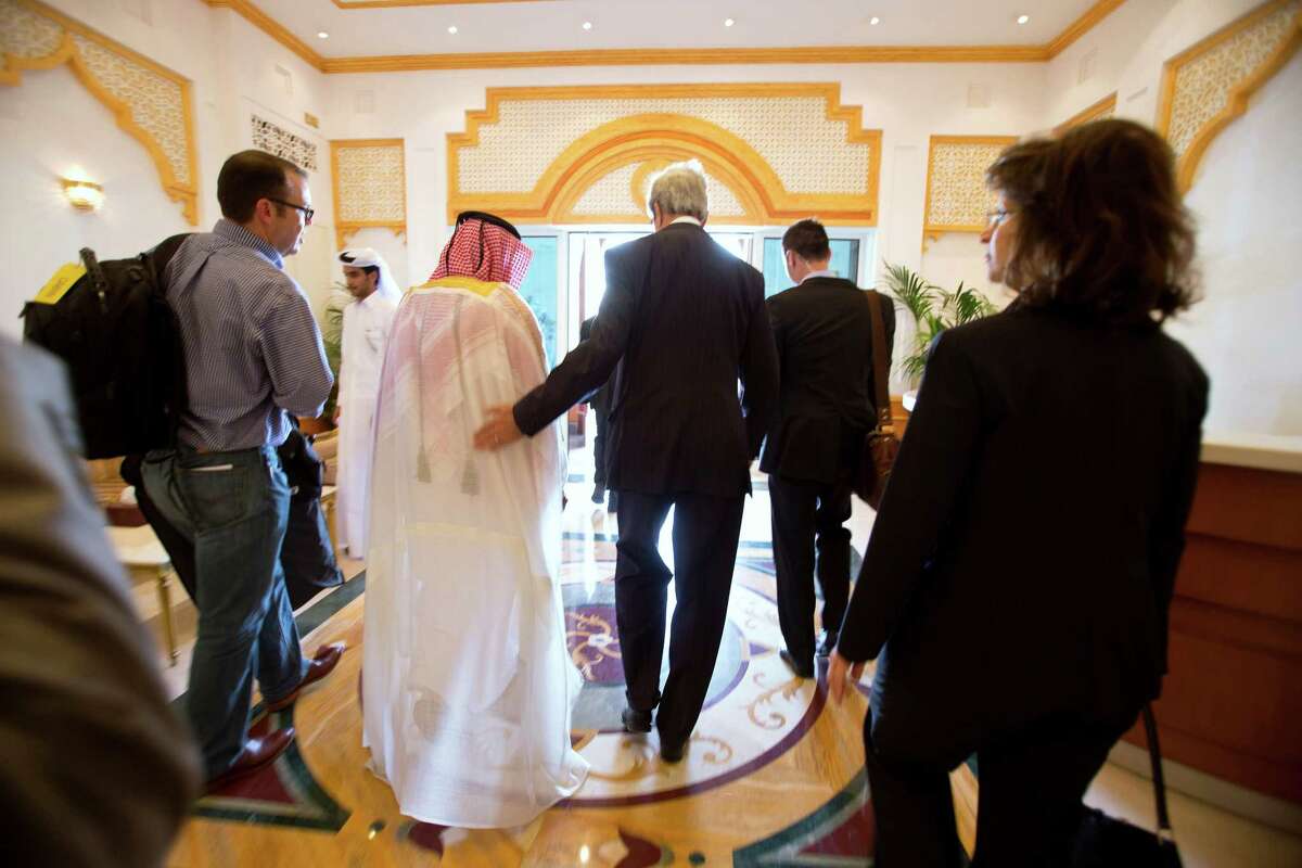 U.S. Secretary of State John Kerry, center, walks through the airport with Ambassador Ibrahim Fakhroo, Qatari Chief of Protocol, left, after being greeted on arrival in Doha, Qatar, on Saturday, June 22, 2013. Kerry began an overseas trip plunging into two thorny foreign policy problems facing the Obama administration: unrelenting bloodshed in Syria and efforts to talk to the Taliban and find a political resolution to the war in Afghanistan. (AP Photo/Jacquelyn Martin, Pool)