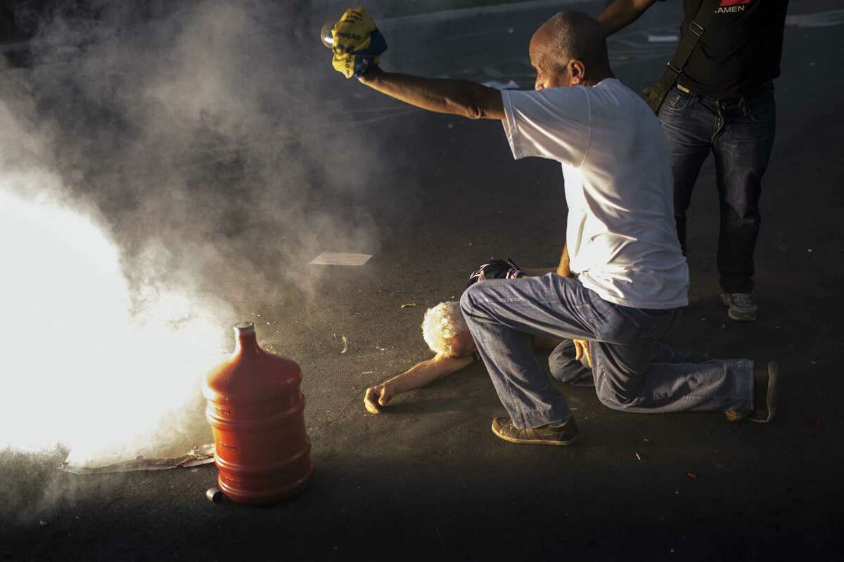 A sound grenade explodes next to an injured man during a protest outside the Minerao stadium in Belo Horizonte, Brazil, during a soccer match.