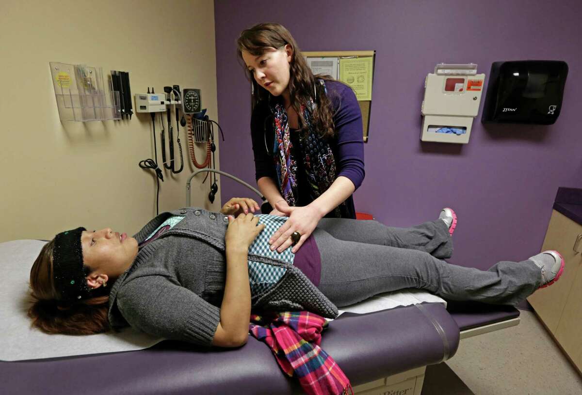 In this March 28, 2013 photo, medical resident Stephanie Place examines Maria Cazho at the Erie Family Health Center, in Chicago. As clinics gear up for the expansion of health insurance, they're recruiting young doctors. (AP Photo/M. Spencer Green)