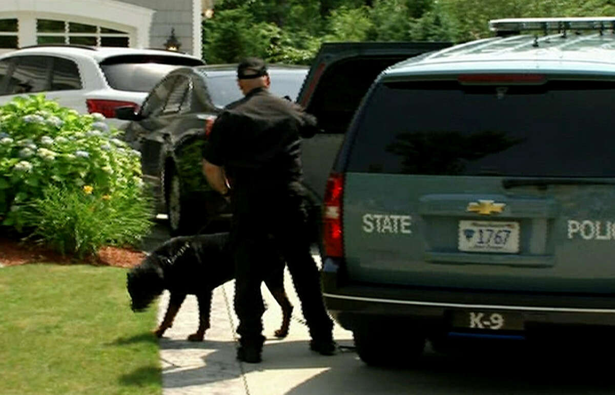 A Massachusetts State Police officer and dog arrive outside the home of Patriots tight end Aaron Hernandez on Saturday in North Attleboro, Mass. The search, involving officers and locksmiths, lasted for more than three hours.