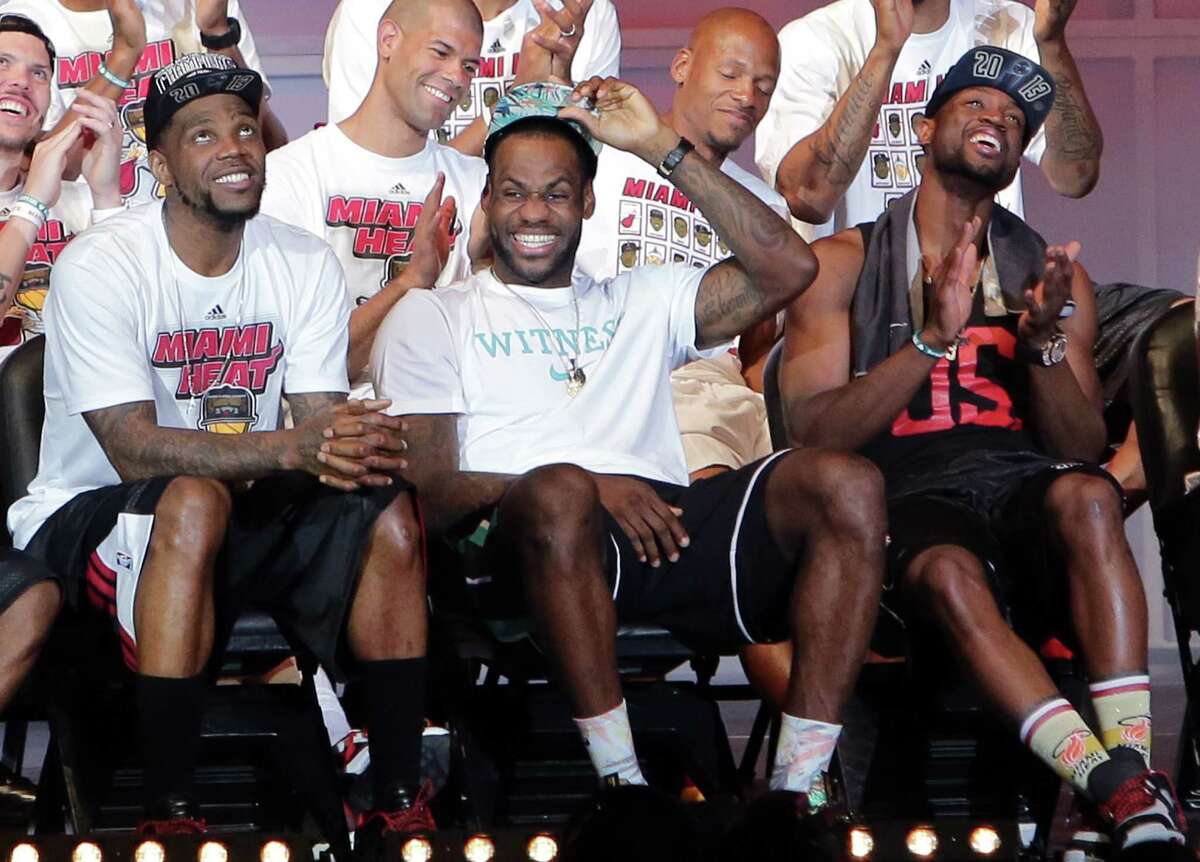 Heat players (front row from left) Udonis Haslem, LeBron James and Dwyane Wade check out the team's highlights on the big screen during their victory rally at AmericanAirlines Arena.