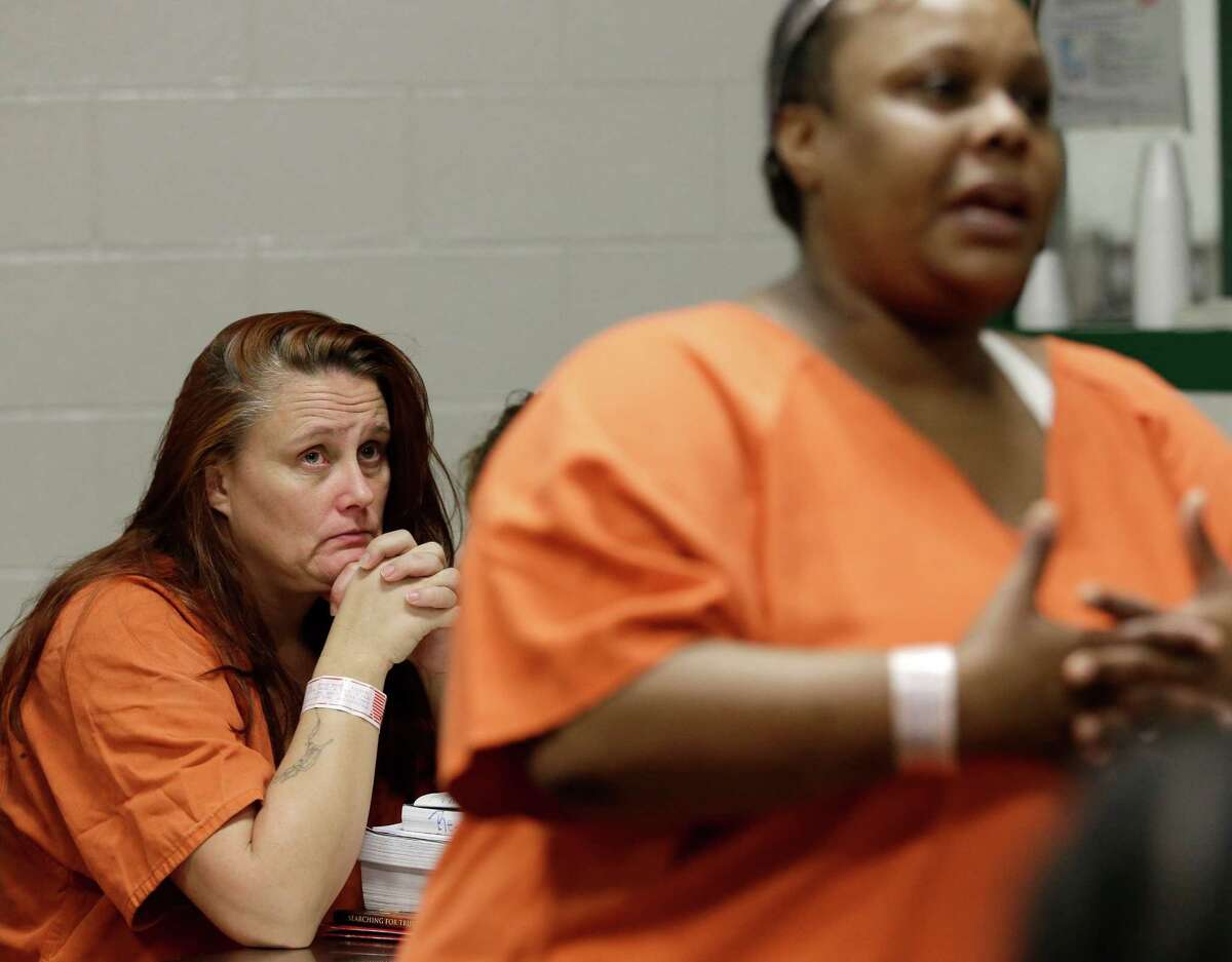 Tricia Chambers, left, watches another inmate tell her story of prostitution during a group meeting in their Harris County cell Tuesday, June 4, 2013, in Houston. Both women are part of a rehabilitation program called We've Been There Done That. (AP Photo/Pat Sullivan)