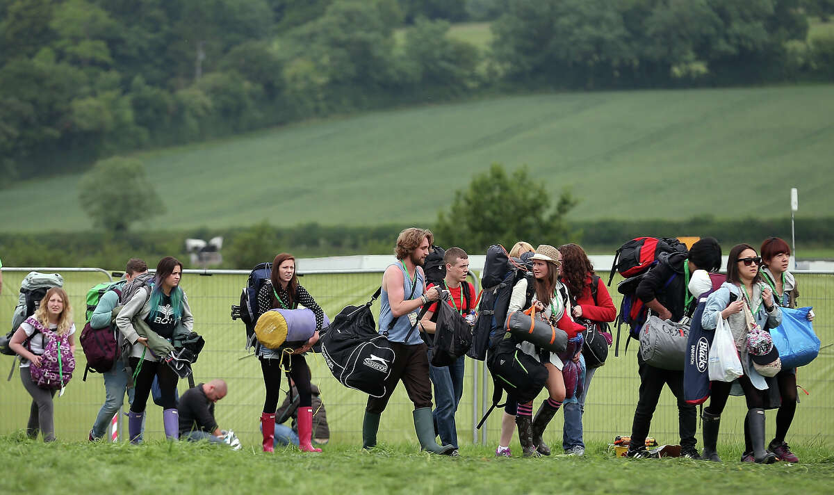 People arrive at the Glastonbury Festival of Contemporary Performing Arts site at Worthy Farm, in Pilton at Worthy Farm, Pilton on June 26, 2013 near Glastonbury, England. Gates opened today at the Somerset diary farm that will be playing host to one of the largest music festivals in the world and this year features headline acts Artic Monkeys, Mumford and Sons and the Rolling Stones. Tickets to the event which is now in its 43rd year sold out in minutes and that was before any of the headline acts had been confirmed. The festival, which started in 1970 when several hundred hippies paid 1 GBP to watch Marc Bolan, now attracts more than 175,000 people over five days.