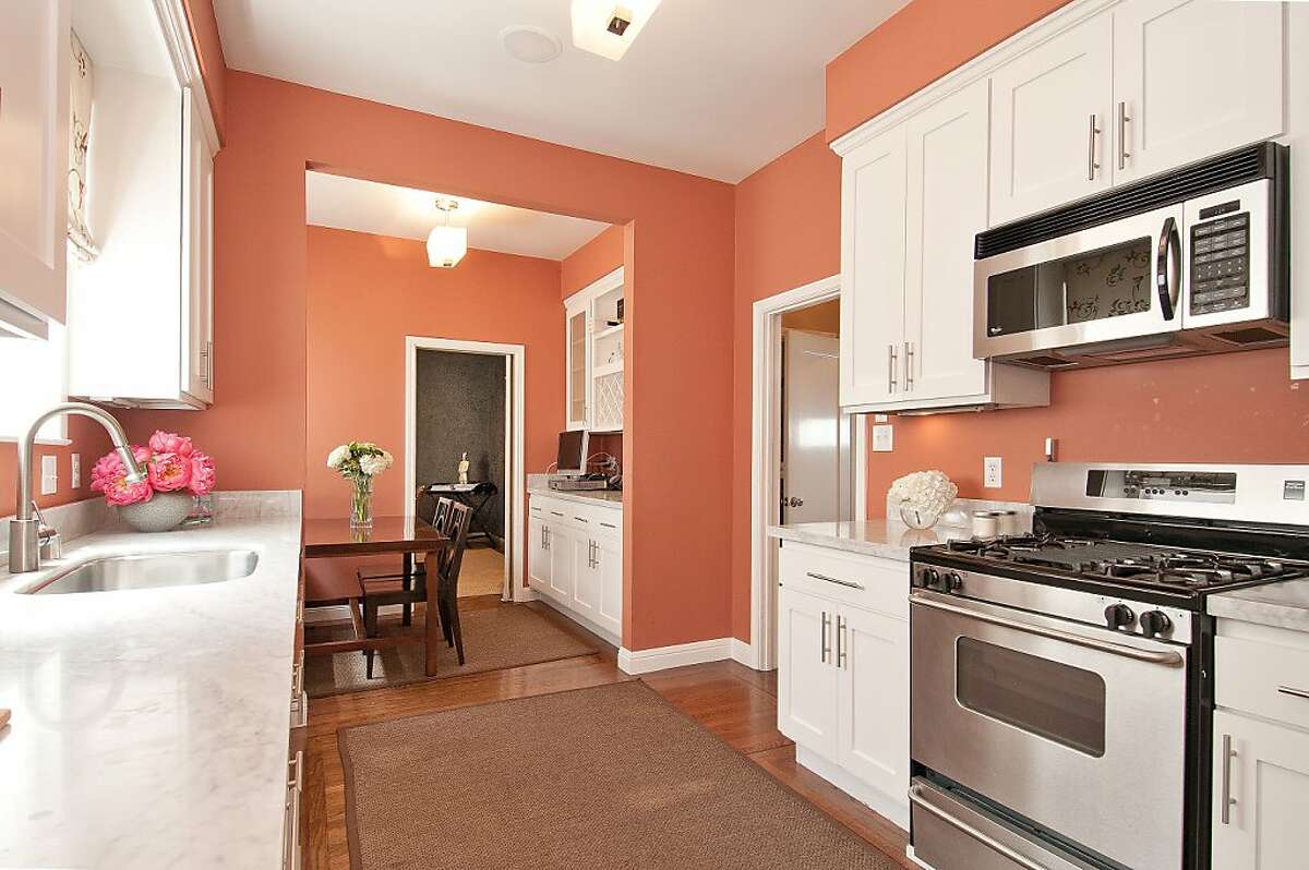 The kitchen includes custom cabinetry and marble countertops and sits beside the breakfast nook.