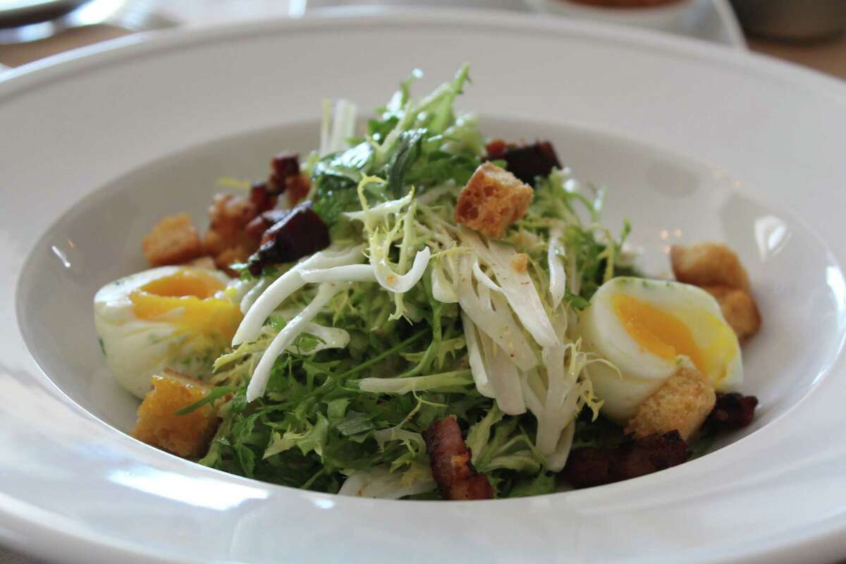 The frisée salad at Minnie's Tavern and Rye House is topped with lardons, poached eggs and vinaigrette.