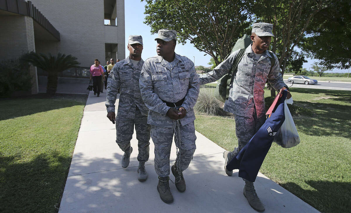 A shackled ex-Senior Airman Christopher Oliver is led away from the 7th Training Wing Headquarters after being sentenced.