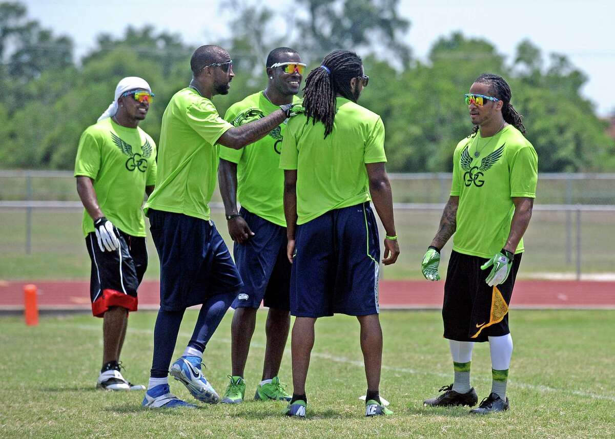 Earl Thomas, right, talks with teammates during Earl Thomas III second annual football camp 7-on7 football game at West Orange-Stark High School on Saturday, June 29, 2013. Photo taken: Randy Edwards/The Enterprise