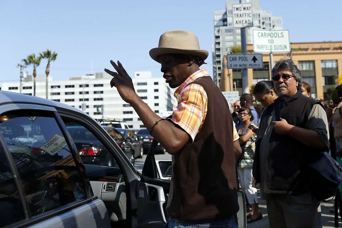 A man puts two fingers in the air gesturing for two more passengers to enter the car at carpool pickup stops on Beale Street while BART workers are on strike in San Francisco, Calif. on July 1, 2013.