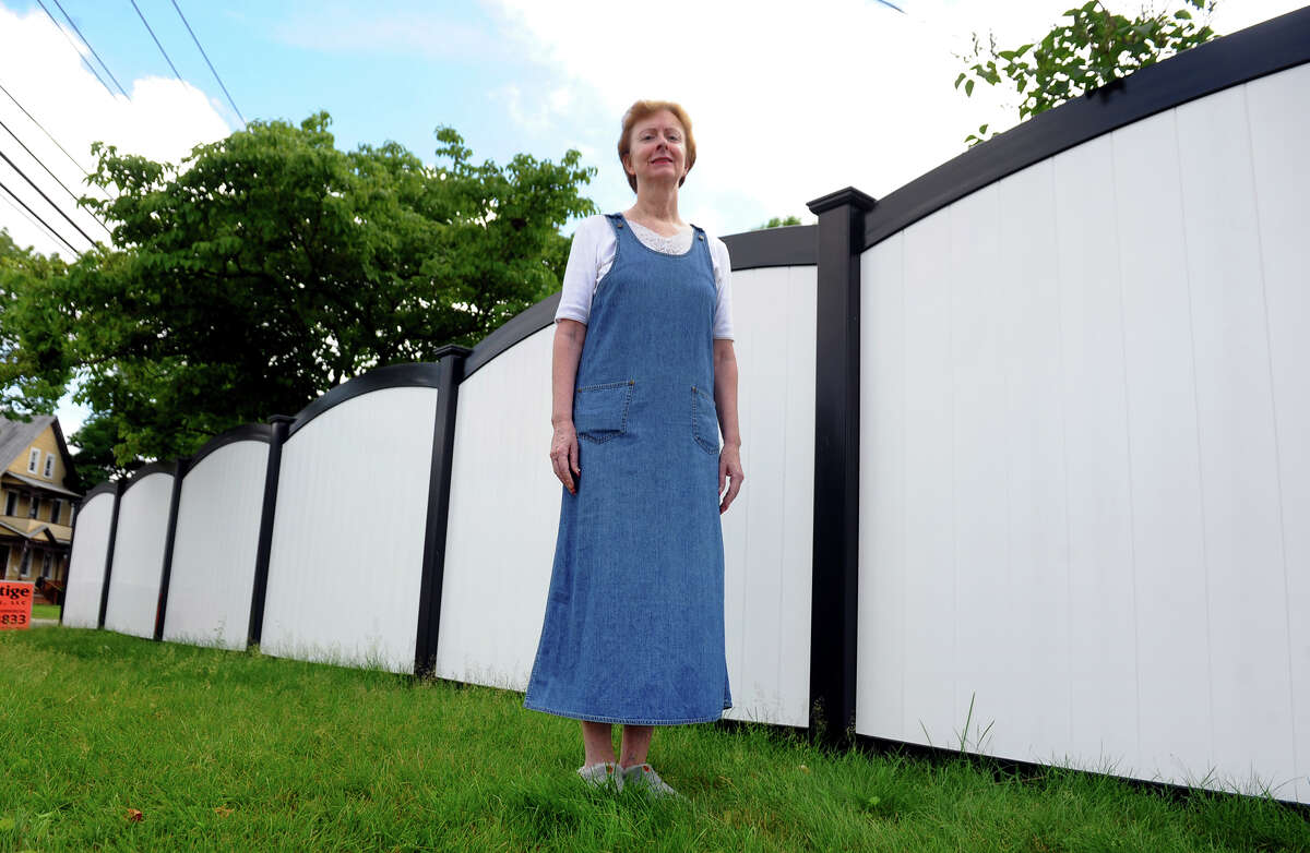 Wakelee Avenue resident Eileen Ryan poses next to a portion of new fence in front of her property in Ansonia, Conn. on Tuesday July 2, 2013. Ryan was replacing the fence after Superstorm Sandy but the town forced her to stop because it was supposedly a violation of city ordinance. On appeal it was overturned by the zoning board of appeals.