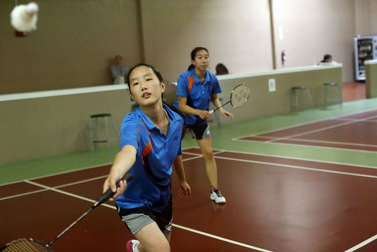 Danae Long, left, returns a shuttlecock while her teammate Sharon Ng, right, watches at the U.S. Badminton team practice at the Bay Badminton Center in Burlingame, Calif. on June 27, 2013.