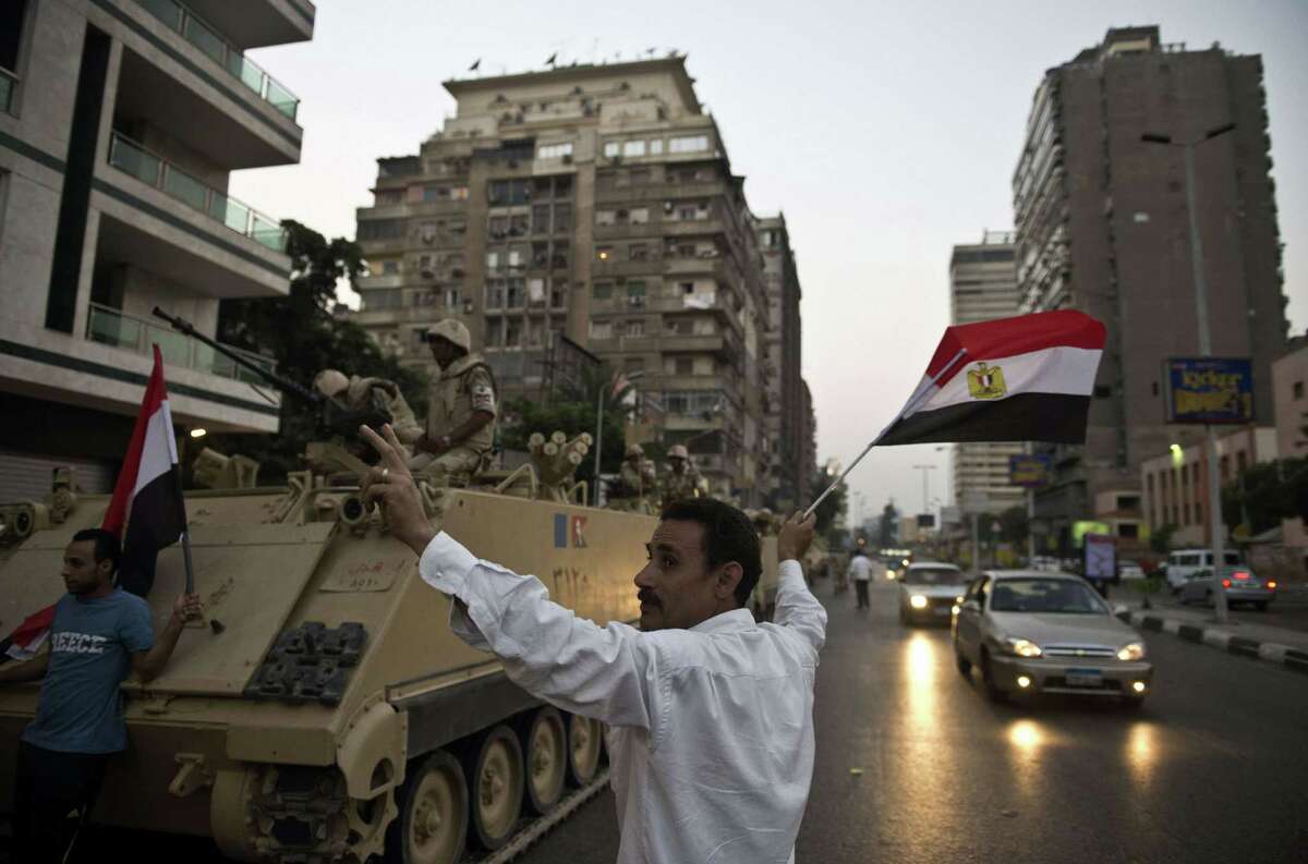 Egyptians salute army tanks upon their deployment on a street leading to Cairo University. A top aide to Egypt's President Mohamed Morsi slammed what he called a "military coup."