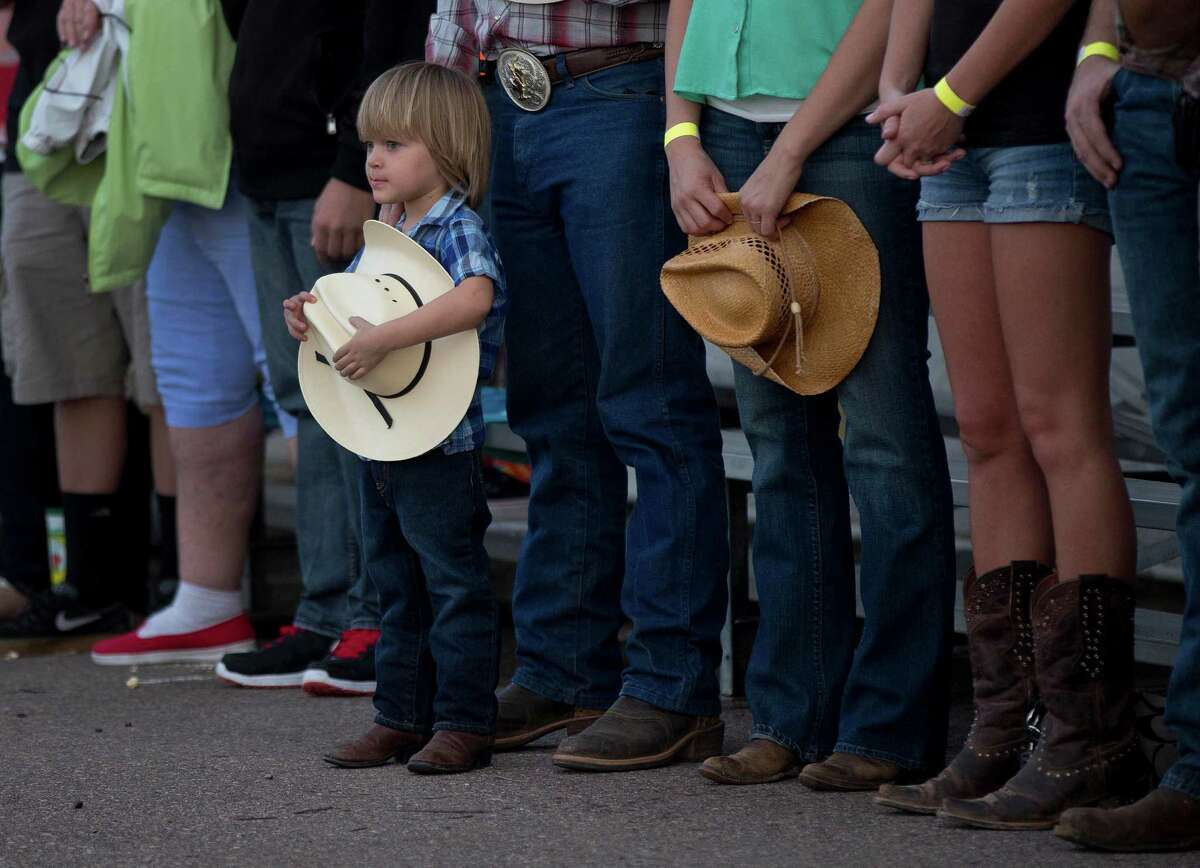 A young boy holds his hat as he and others stand for the national anthem before the start of the Prescott Frontier Days Rodeo, Wednesday, July 3, 2013 in Prescott, Ariz. A mile-high city about 90 miles northwest of Phoenix, Prescott remains a modern-day outpost of the pioneer spirit. It's that spirit that will guide officials as they navigate the days ahead and figure out how to honor the elite Hotshot firefighters who died in a nearby wind-driven wildfire that is still burning. (AP Photo/Julie Jacobson)