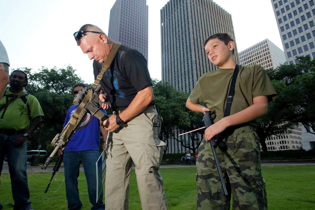 Ed Aldredge of Sugar Land makes sure there's no round in the chamber of his AR-15, or in his son Austin's .22-caliber rifle, as they joined a group of some two dozen demonstrators with the gun-rights group Come and Take it Houston.