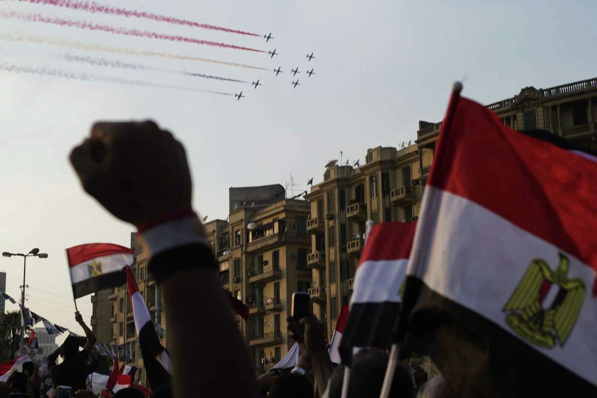 Egyptians cheer and wave national flags as airplanes fly past Tahrir Square, trailing smoke in the colors of the national flag on Thursday in Cairo.