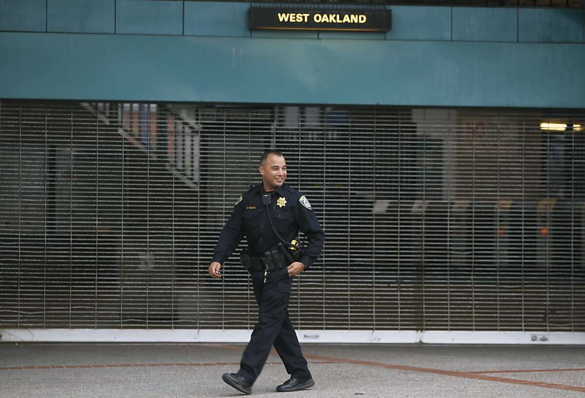 A BART police officer patrols in front of the West Oakland station in Oakland, Calif. on Friday, July 5, 2013. BART service will resume at 3pm Friday after union employees agreed to suspend their strike for 30 days while negotiations continue.