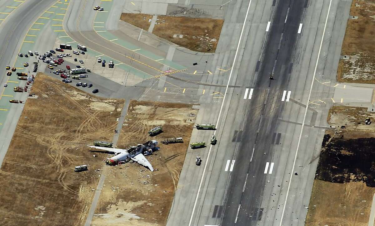The destroyed fuselage of Asiana Airlines Flight 214 is visible on the runway at San Francisco International Airport after it crashed on landing and burned on Saturday, July 6, 2013.
