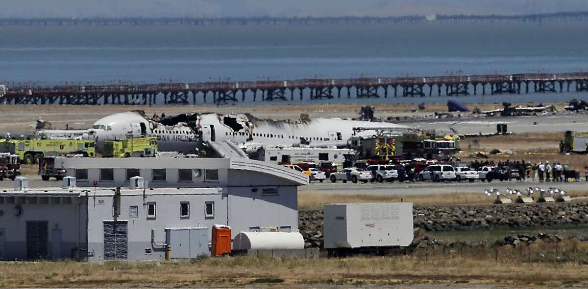The wreckage of Asiana flight 214 sits beside the runway in San Francisco, Calif., on Saturday July 6, 2013, following a crash landing this morning at San Francisco International airport.