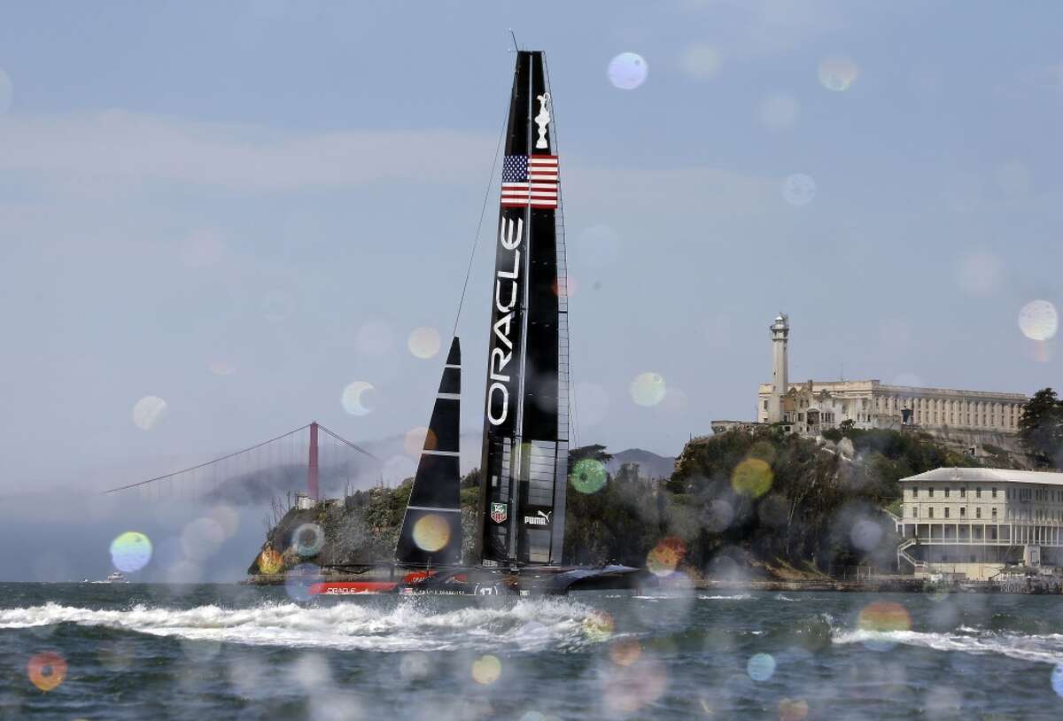 An Oracle Team USA catamaran sails past Alcatraz Island with the Golden Gate Bridge in the background during training for the America's Cup, Wednesday, July 3, 2013, in San Francisco. Opening ceremonies for the sailing event are scheduled for Thursday. (AP Photo/Eric Risberg)