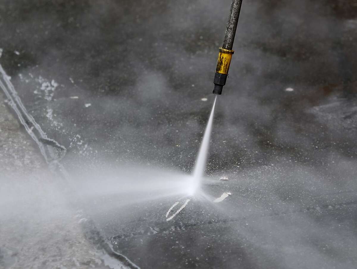 Stephen Lee, from the Department of Public Works, uses a power washer to remove sticky material from a sidewalk on Jessie Street near Sixth Street in San Francisco, Calif. on Wednesday, July 10, 2013.