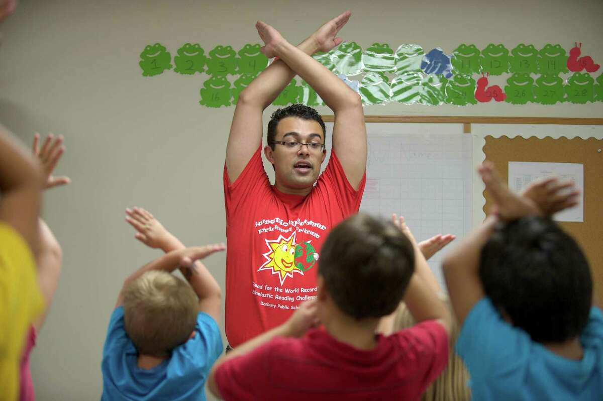 Instructor Hans Guardado leads the class in the "alphabet stretch" where they make the shapes of the letters in the alphabet, during the OWL Club. It is part of the Sunsational Summer Enrichment Program by the Danbury Public Schools and is meant to prevent summer learning loss by students. The program takes place at Rogers Middle School, in Danbury Conn. Thursday July 11, 2013.