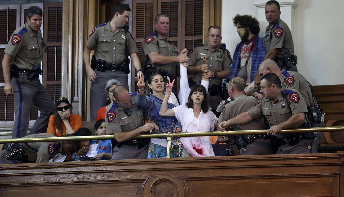 DPS troopers arrest protesters who chained themselves to a railing in the gallery.