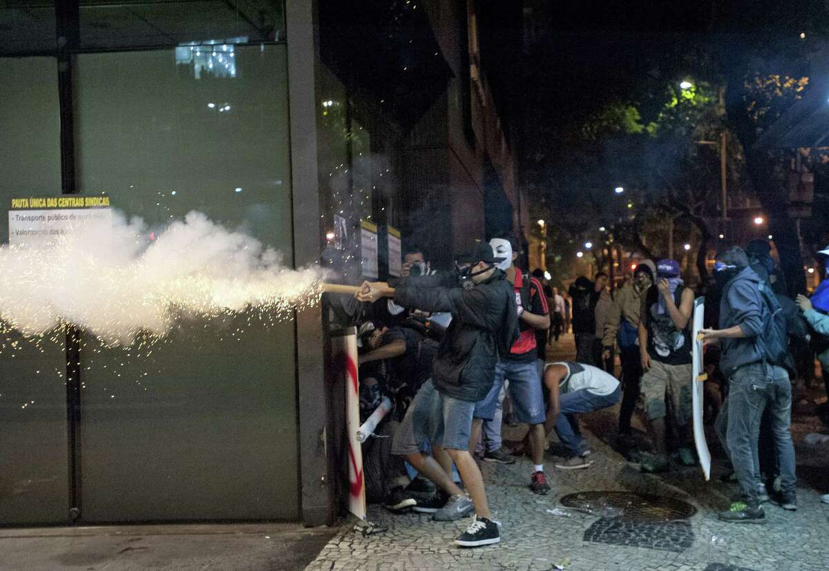A masked demonstrator shoots a firework at police during a union-organized strike in Rio de Janiero. Brazilian law enforcement has struggled containing the wave of protests nationwide.