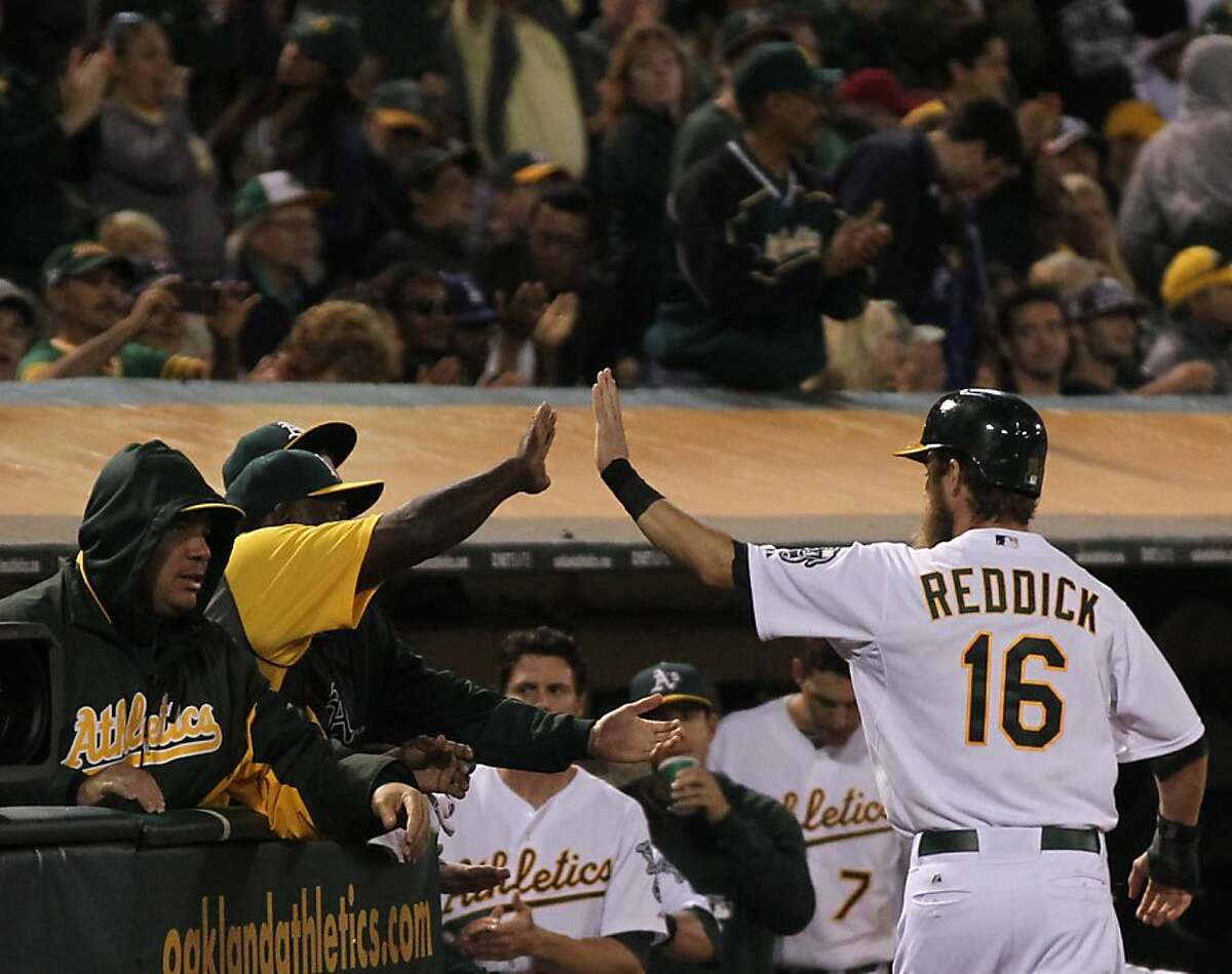Oakland Athletics Josh Reddick is greeted at the dugout after scoring on a RBI single by Coco Crisp in the 7th inning of their MLB baseball game with the Boston Red Sox Saturday, July 13, 2013, In Oakland CA.