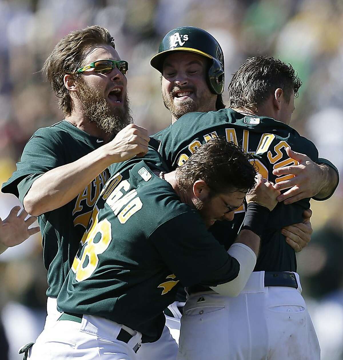 Oakland Athletics' Josh Donaldson, right, is mobbed by teammates, including Eric Sogard (28) and Josh Reddick, left, after Donaldson hit the game-winning single in the 11th inning of a baseball game against the Boston Red Sox on Sunday, July 14, 2013, in Oakland, Calif. The A's won 3-2. (AP Photo/Ben Margot)