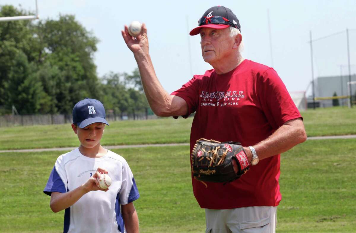 Major League Baseball Hall of Famer Phil Niekro helps Max Chermayoff, 12, of Rowayton, with his knuckleball at a Baseball World Training School in Westport, Conn. on Monday, July 15, 2013.