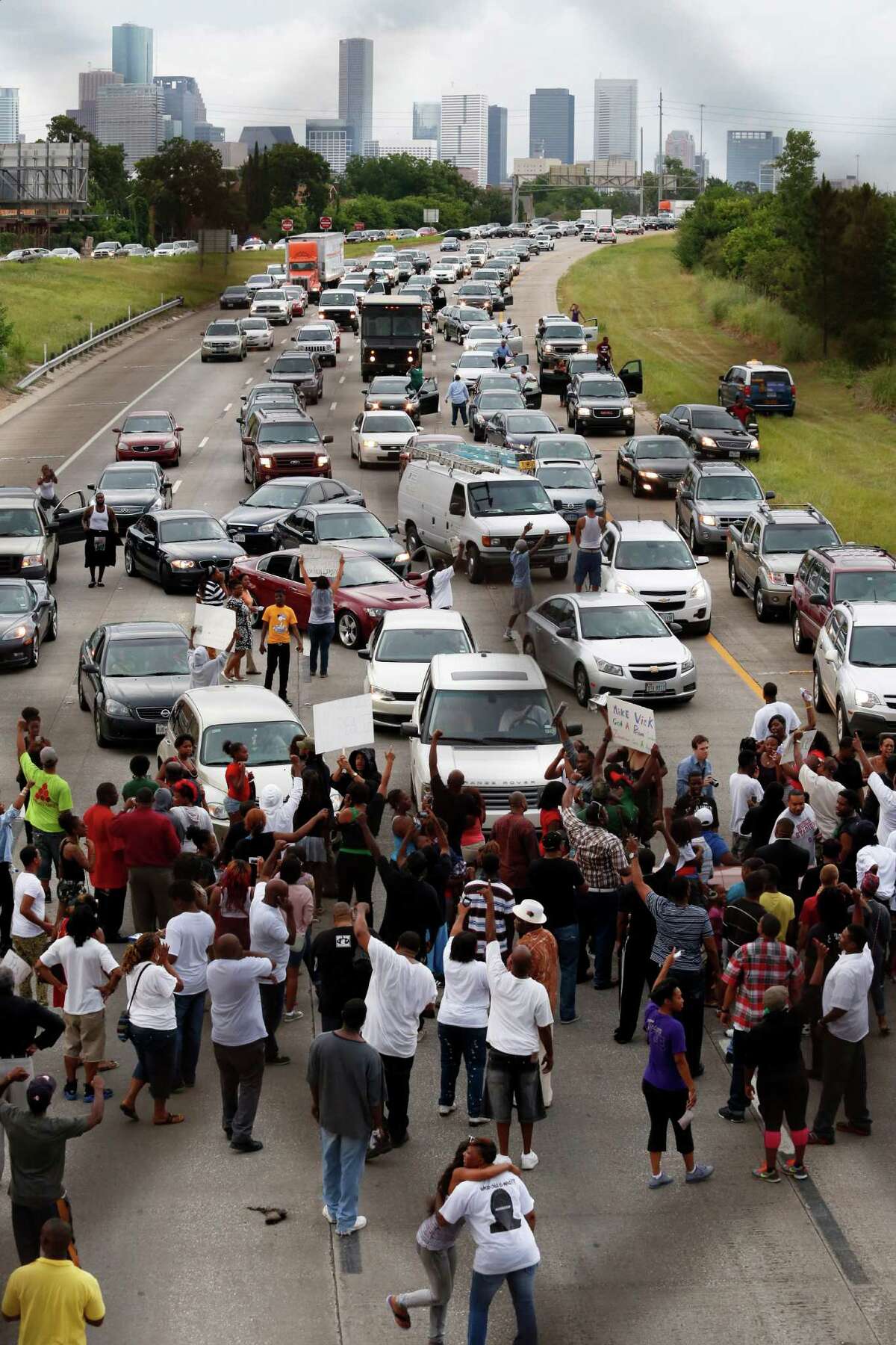 Protesters stop traffic on Texas 288 Monday, above, as activist Quanell X, at right, and local community leaders and hip-hop stars lead a protest that began at the Byrd Funeral Home on Wheeler.