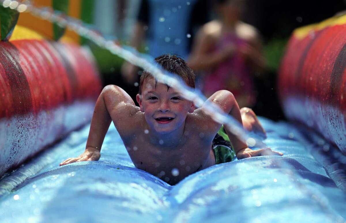 Camper Logan Page, 7, of Shelton, cools off on a slip n' slide Tuesday, July 16, 2013 during day camp at Harbor Light Summer Adventures in Fairfield, Conn.