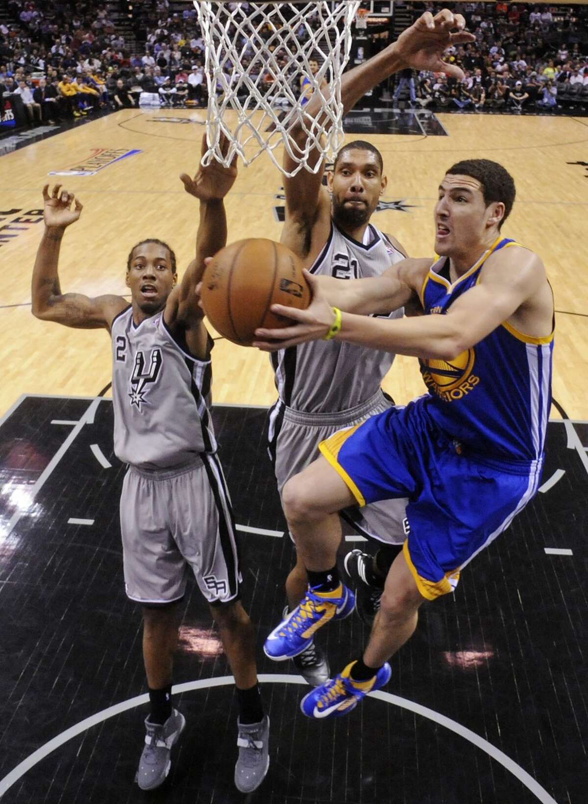 Golden State Warriors' Klay Thompson shoots around San Antonio Spurs' Kawhi Leonard and Tim Duncan in 2013.