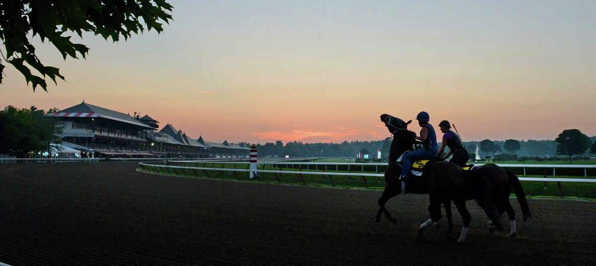 Horses trained by Glen DeSanto go out for their morning exercise as the sun rises Thursday morning, July 18, 2013, at Saratoga Race Course in Saratoga Springs, N.Y. The 150th race meet begins Friday. (Skip Dickstein/Times Union)