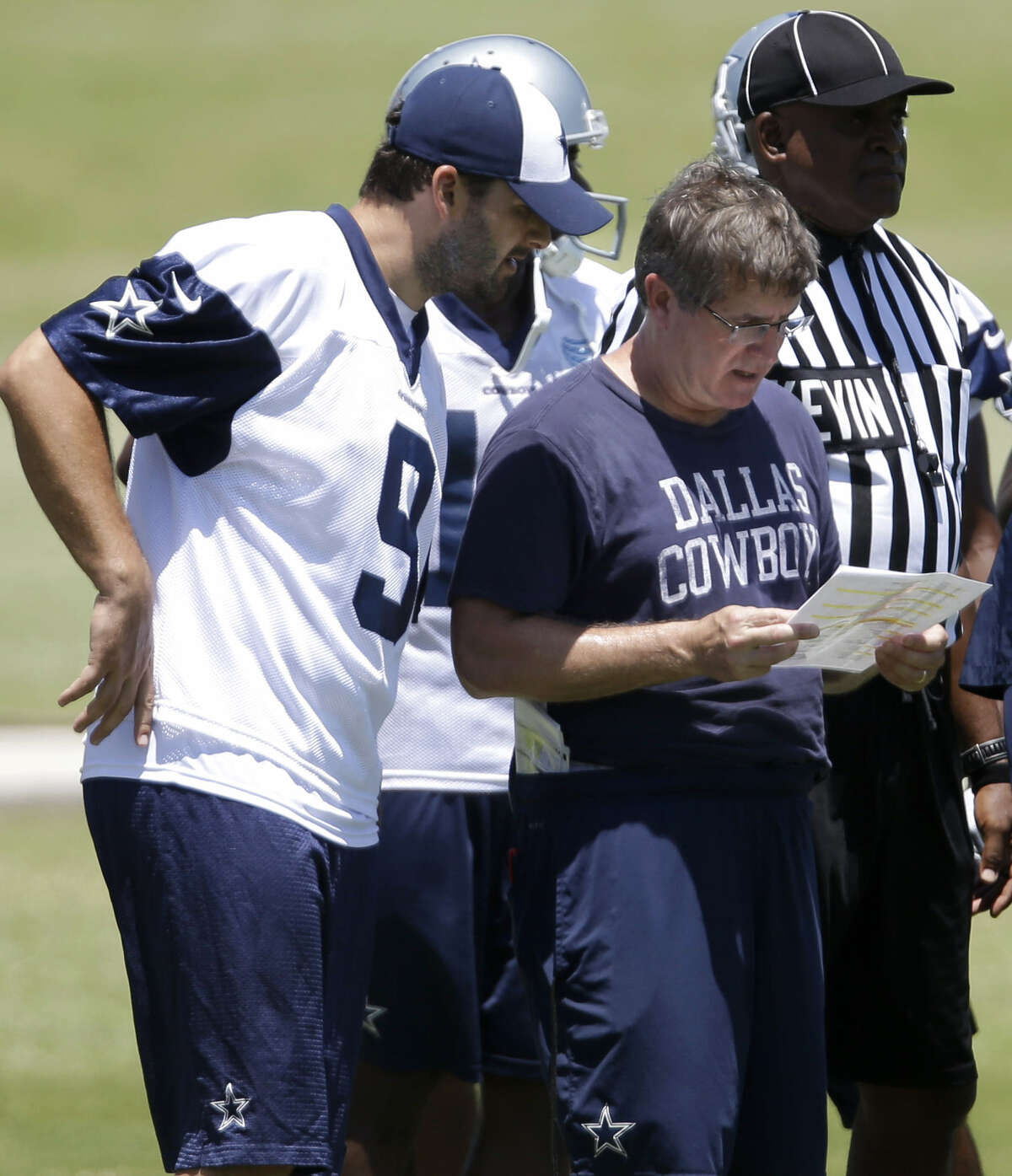 Cowboys QB Tony Romo (9) looks over plays with offensive coordinator Bill Callahan, who has been a proponent of a physical running game, as they run drills during a minicamp last month.