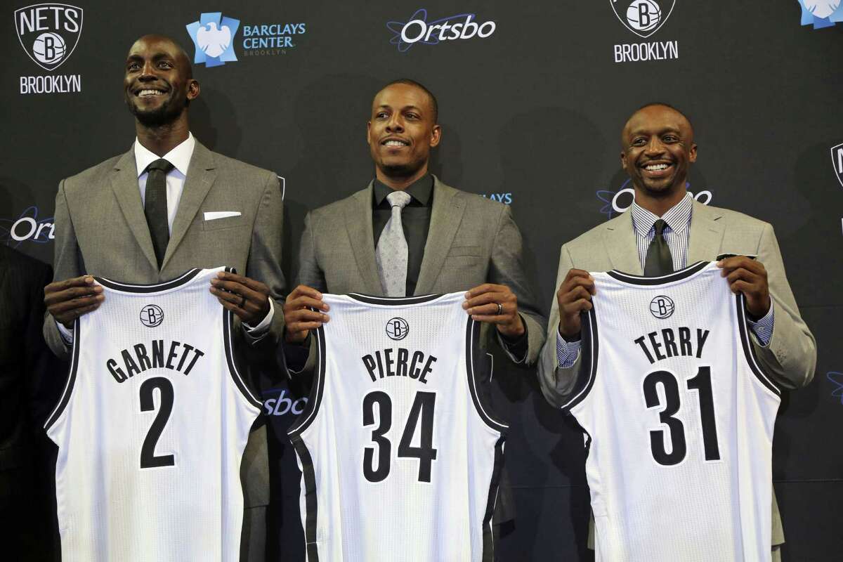 New Brooklyn Nets (from left) Kevin Garnett, Paul Pierce and Jason Terry show off their new jerseys. Pierce appeared to be the most affected by the reality of the trade from Boston.