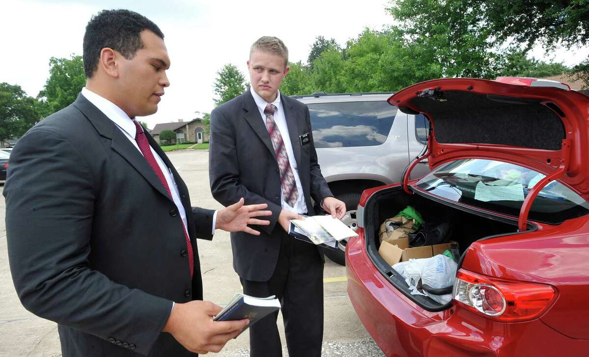Elder Beaver Ho Ching, left, talks about some of the content in the pamphlets they hand out going door-to-door as Elder Joshua Limb, right, pulls more from their trunk. Officials with the Church of Jesus Christ of Latter Day Saints, (Mormons), recently announced they would extend missionary service to the Internet and other mobile platforms to reach out to more people, possibly ending, or cutting down the amount of time spent on the practice of door-to-door missionary work in the future. Dave Ryan/The Enterprise