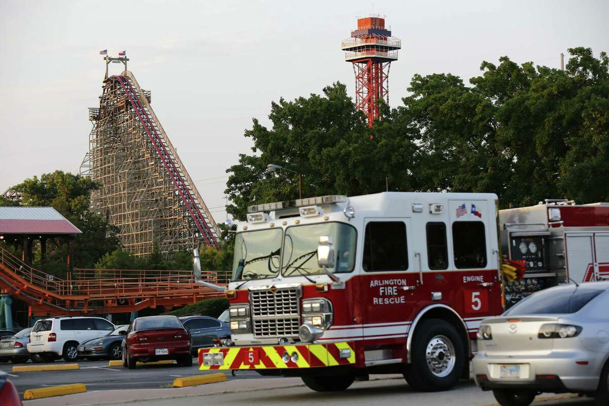 Emergency personnel are on the scene at Six Flags Over Texas in Arlington, Texas, after a woman died on the Texas Giant roller coaster, background left, on Friday, July 19, 2013. (AP Photo/The Dallas Morning News, Tom Fox) MANDATORY CREDIT; MAGS OUT; TV OUT; INTERNET USE BY AP MEMBERS ONLY; NO SALES