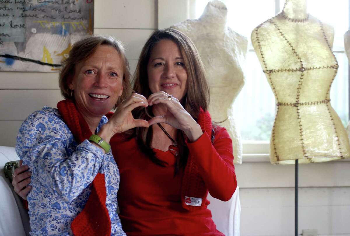 Rebecca Trahan, left and Lisa Hulick, right, show off one of several hand knitted red scarves as they talk about their separate heart attacks, Tuesday, July 2, 2013, in Houston. The two young and fit women, relatively recently, recovered from major heart surgeries. They've started a support group called WomenHeart for other women with heart disease. ( Karen Warren / Houston Chronicle )