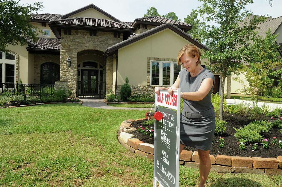 Realtor Robyn Brand, The Woodlands, places a for-sale sign on the lawn of a house at 70 Player Crest in The Woodlands.