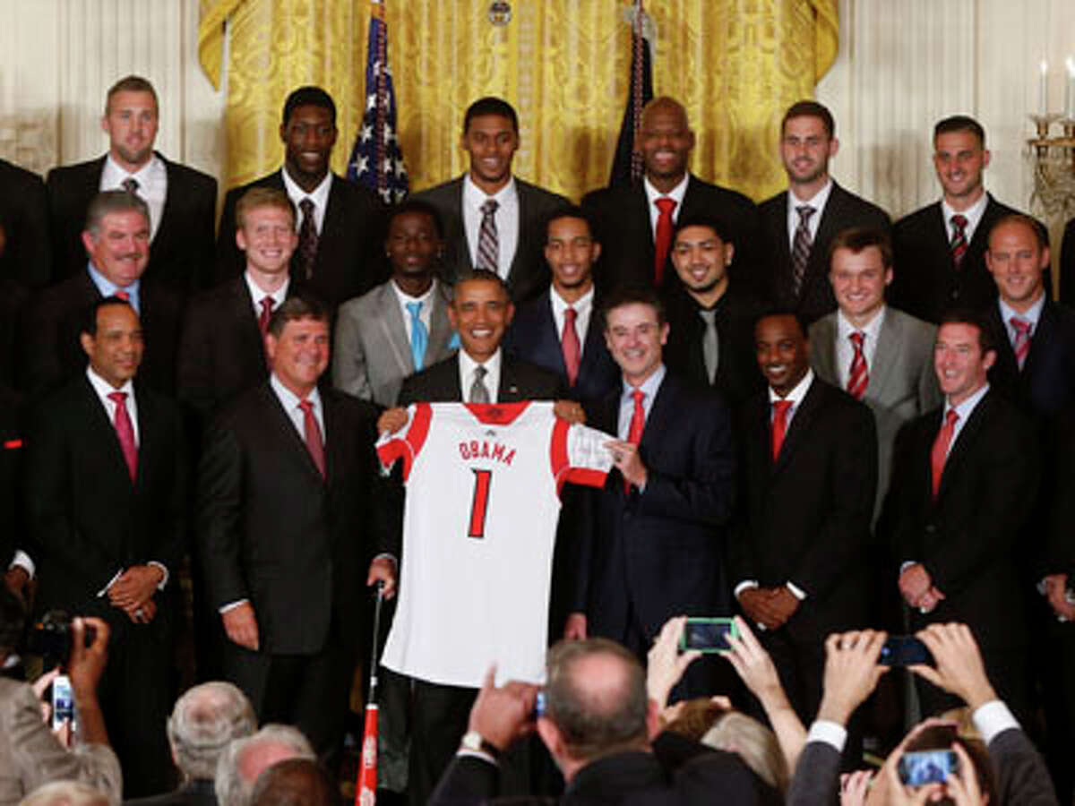President Barack Obama holds up a Louisville basketball jersey presented to him by coach Rick Pitino, next to the president, right, as he honored the 2013 NCAA Men’s Basketball Champions Louisville Cardinals, Tuesday, July 23, 2013, in the East Room at the White House in Washington.