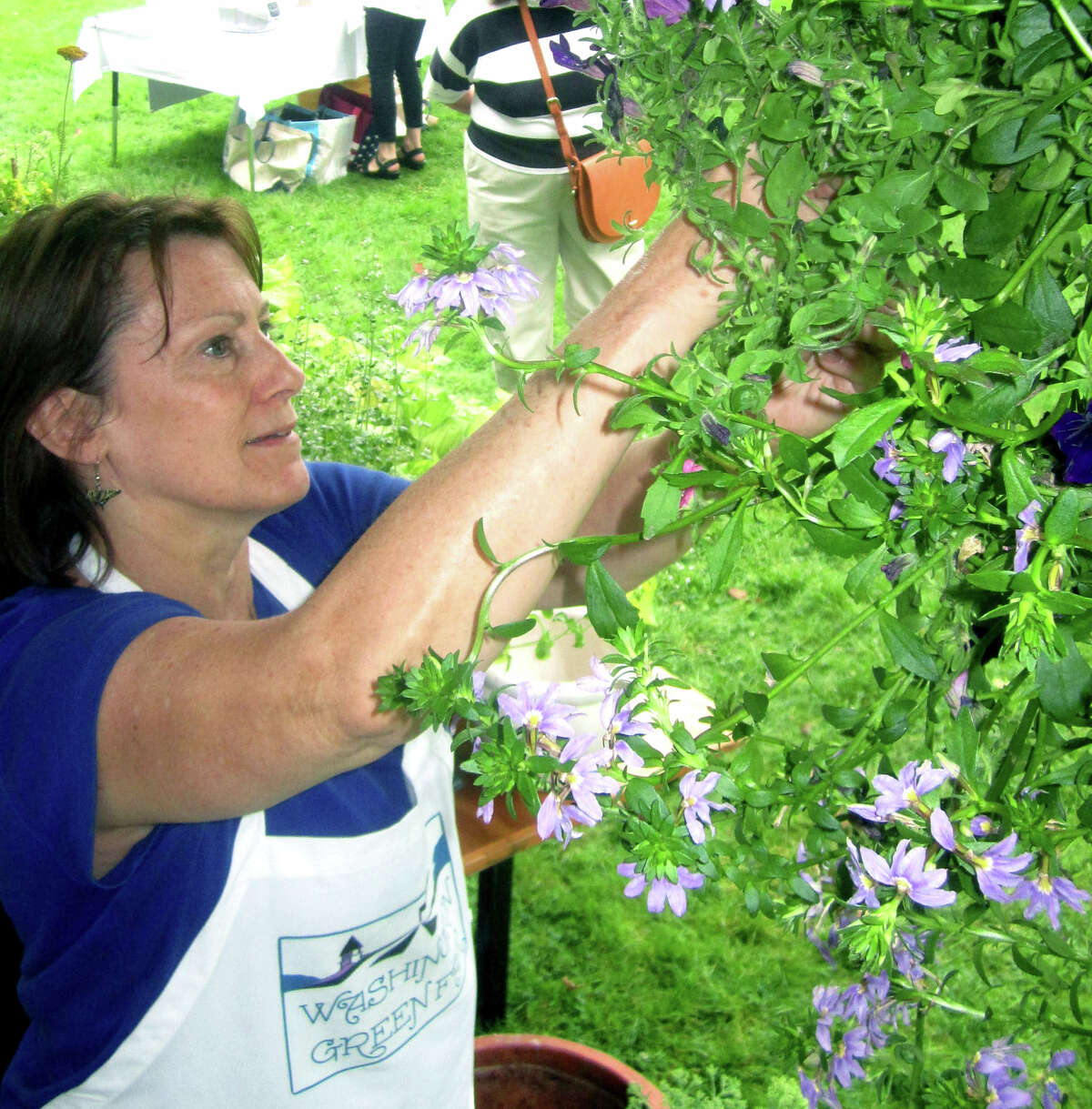Sue Elliott of Litchfield, a church member, makes sure the hanging plants look just right for patrons of the Washington Congregational Church's annual Green Fair, July 13, 2013.