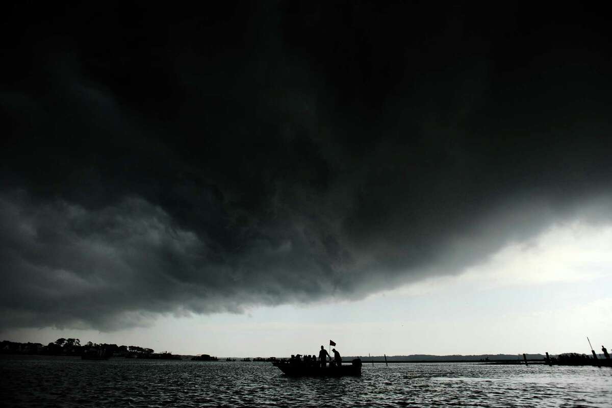 A boat in Assateague Channel is dwarfed by a thunderstorm cloud just before the Chincoteague Ponies hit the water for their annual swim to Chincoteague, Va. on Wednesday, July 24, 2013. The storm brought heavy rain as the ponies made the 88th annual swim.
