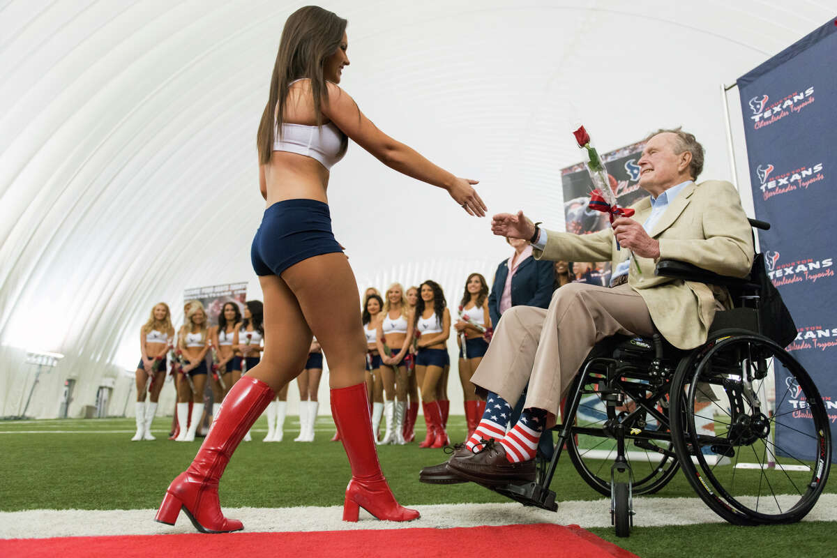 Former President George H.W. Bush presents a rose to a newly announced Houston Texans cheerleader during a ceremony announcing the new squad at the Texans training facility. The new squad will debut at the Texans' draft party at Reliant Stadium on April 25.