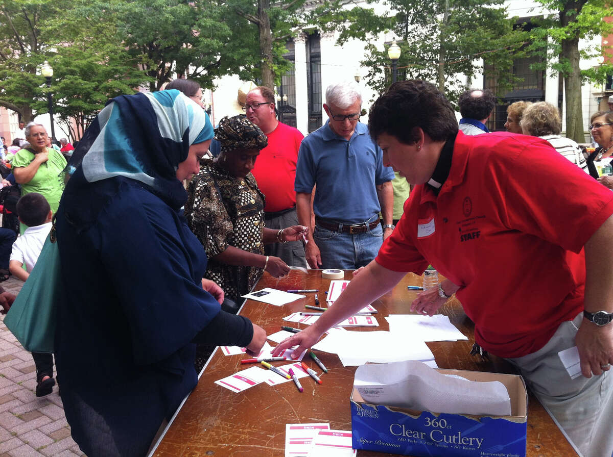 Rev. Sara Smith, of the United Congregational Church, gives Bridgeport resident Rita Hassan a name tag for an interfaith event about the Muslim observance of Ramadan in downtown Bridgeport on Sunday, July 28, 2013.