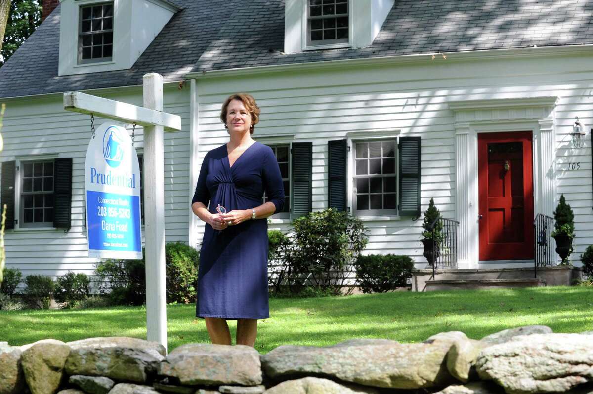 Liz Bacon of Prudential Realty stands in front of house in Darien for 8.1 property rounds at Darien, Conn., Monday, July 29, 2013.