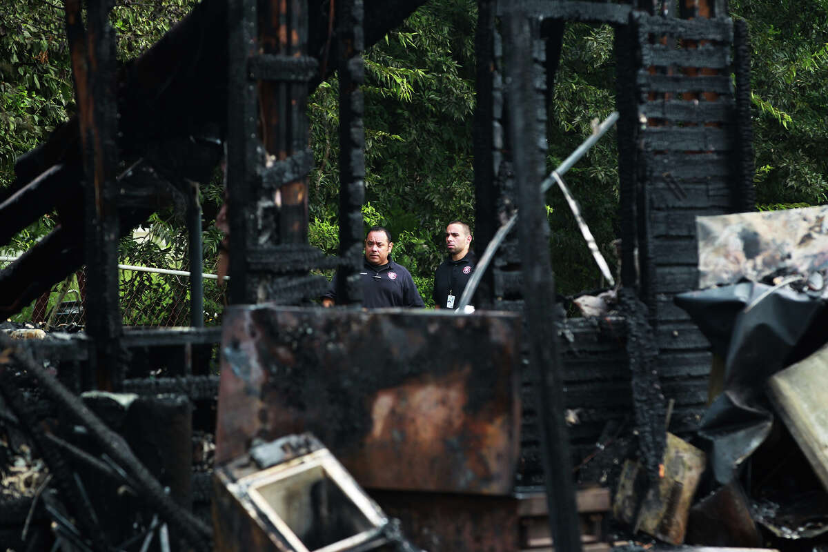 Personnel with the City of San Antonio Development Services Department inspect damage to a home on the 1,000 block of Sams Drive on the city's South Side that burned down shortly after 6:00 a.m. Tuesday July 30, 2013. Fire officials said one person was transported to an area hospital with non-life threatening injuries. Michelle Garza, who said she lived at the home, said 12 people were in the house at the time of the fire.