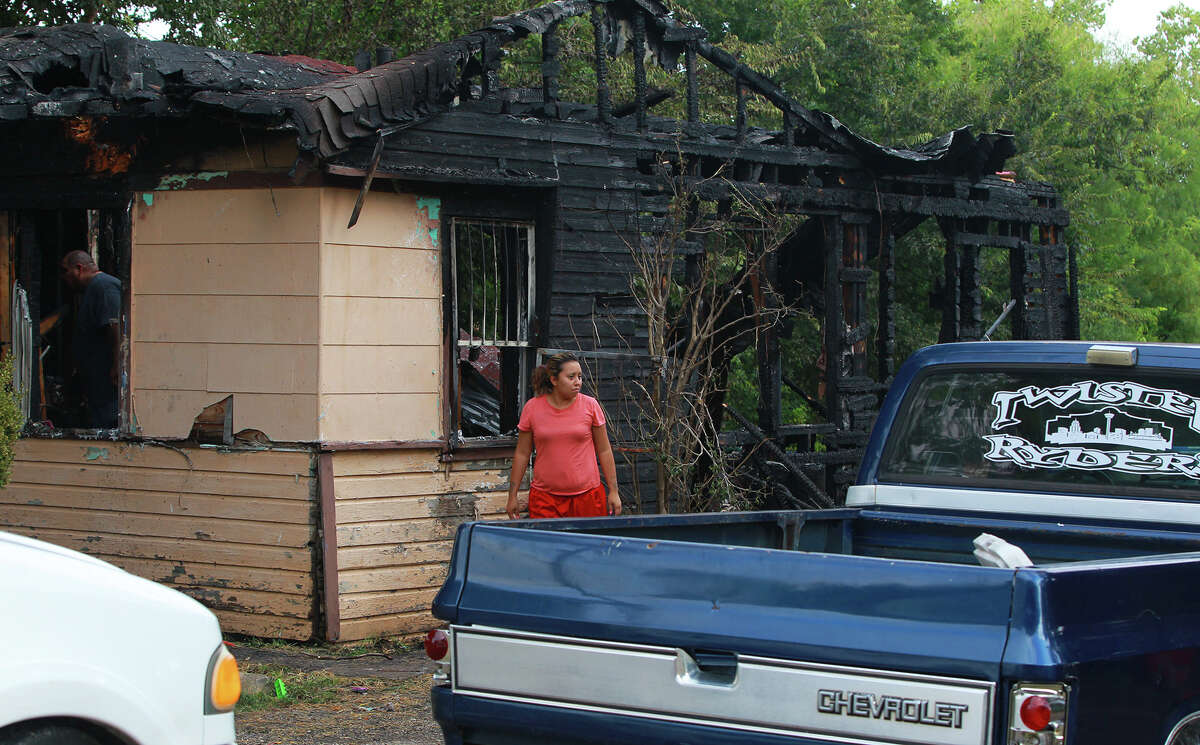 Michelle Garza (center) inspects damage to a home on the 1,000 block of Sams Drive on the city's South Side that burned down shortly after 6:00 a.m. Tuesday July 30, 2013. Fire officials said one person was transported to an area hospital with non-life threatening injuries. Michelle Garza, who said she lived at the home, said 12 people were in the house at the time of the fire.