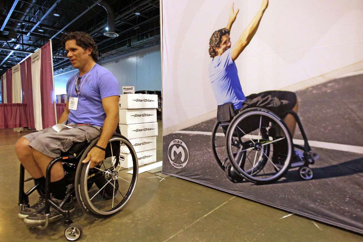 Russell Rodriguez, of Nashville, appears to do double duty while setting up a SmartDrive display that also features his image, right. The SmartDrive is a motion-activated power assist device for manual wheelchairs.